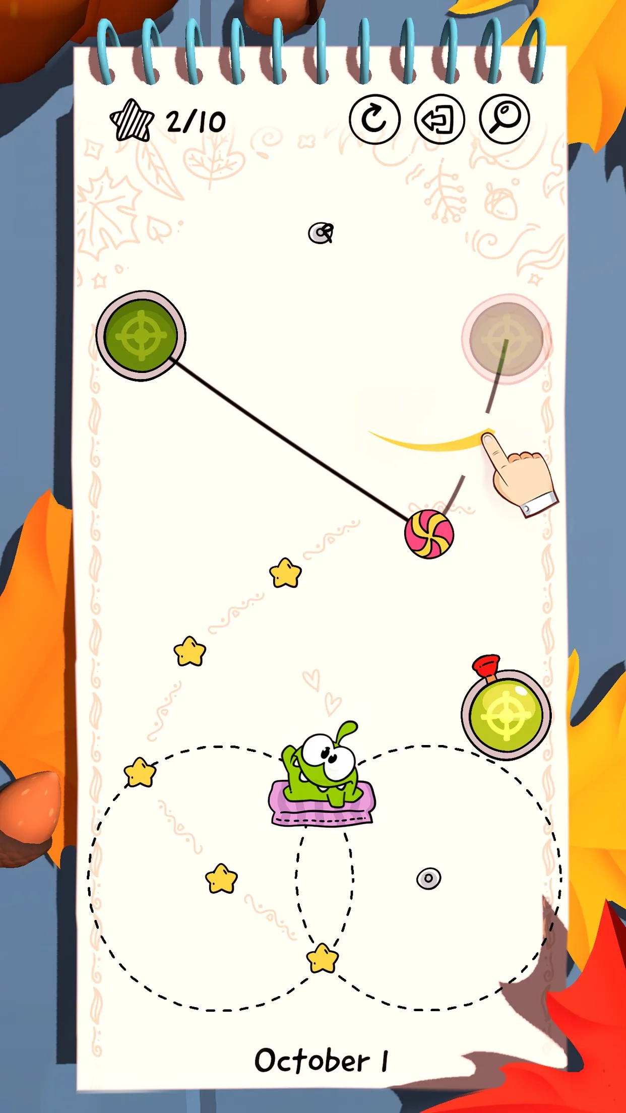 Cut the Rope Daily's October 1 level in an autumn setting: a finger swipes a rope, candy swings toward stars, Om Nom sits between two dashed rope circles