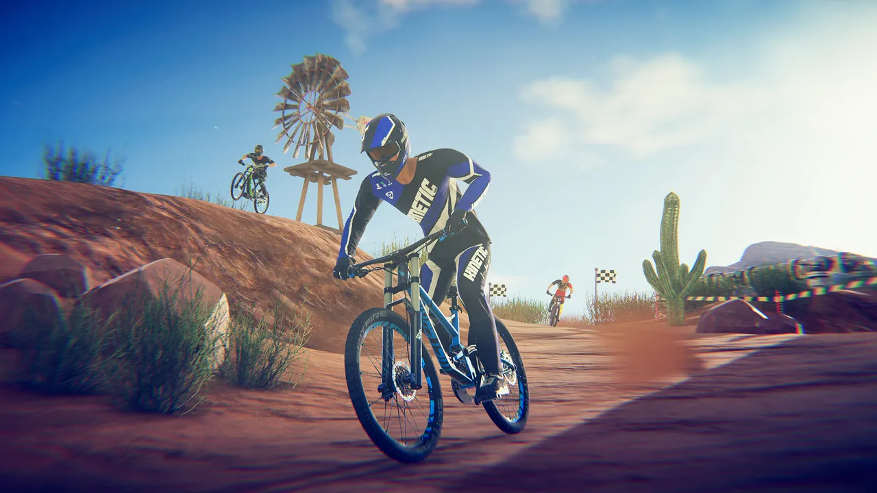 Descenders: a rider in blue gear on a desert track with a windmill, a cactus and other riders behind