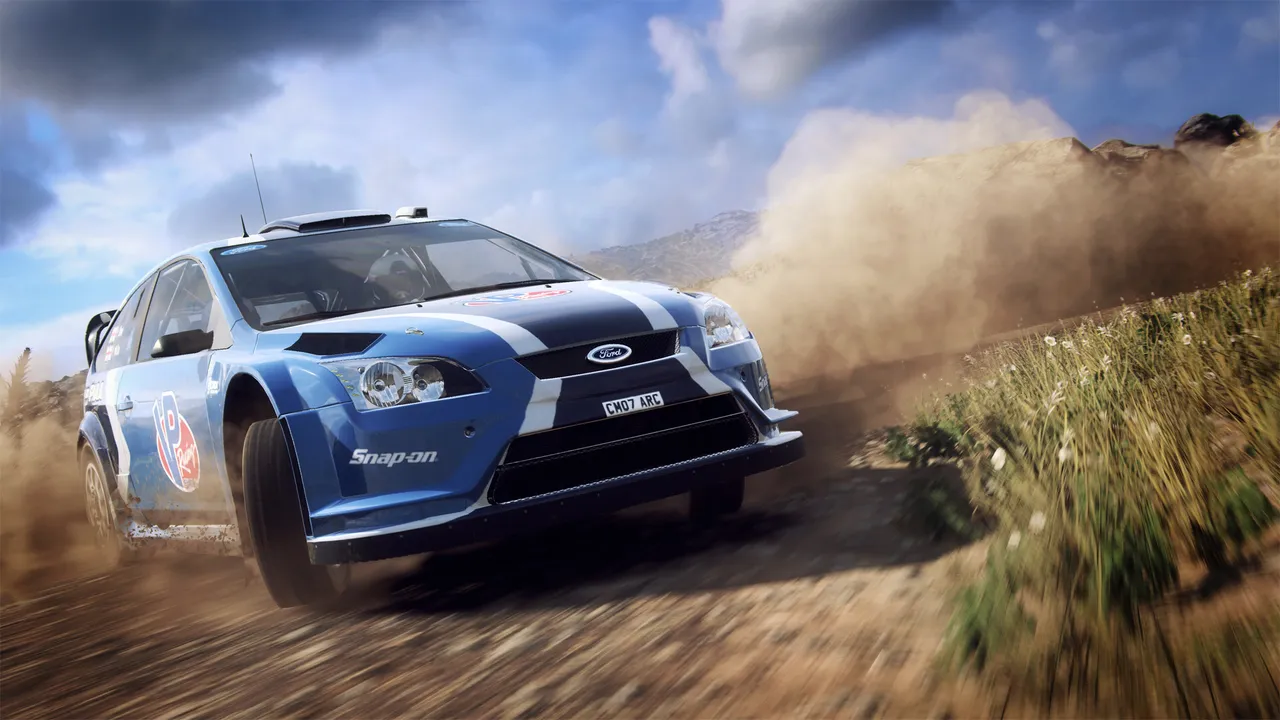 A blue Ford Focus rally car throws up dust on a gravel stage in DiRT Rally 2.0