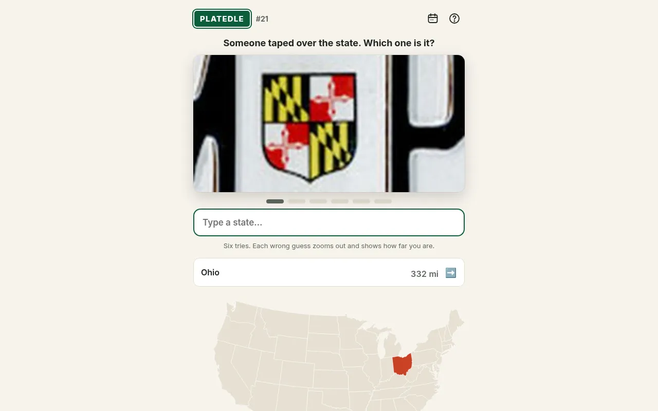 Platedle plate #21 after one wrong guess: a close-up of the Maryland flag shield on a plate, Ohio listed as 332 miles off with an arrow east, and Ohio shaded on the US map