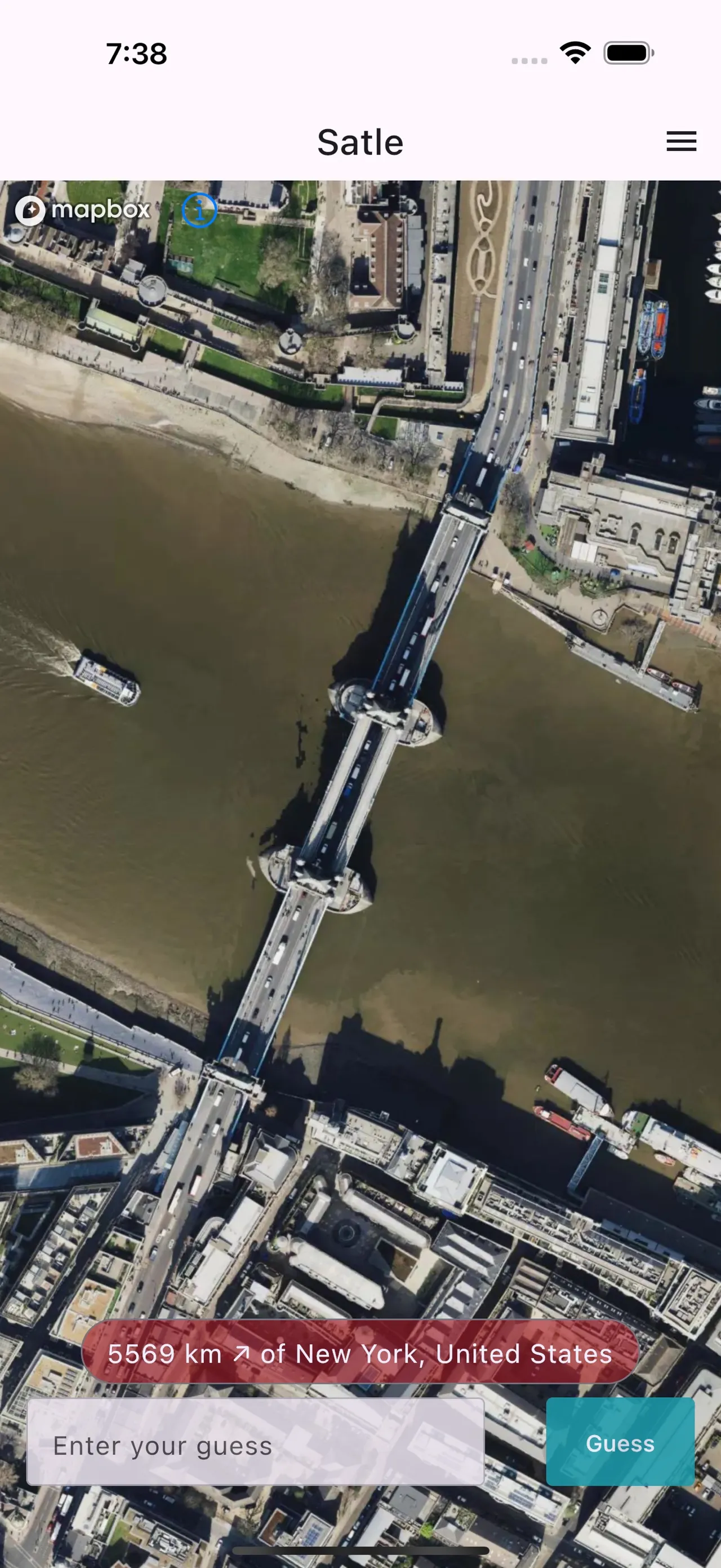 Satle zoomed out after a wrong guess: the bridge and riverbanks from above with a banner reading 5569 km north-east of New York, United States