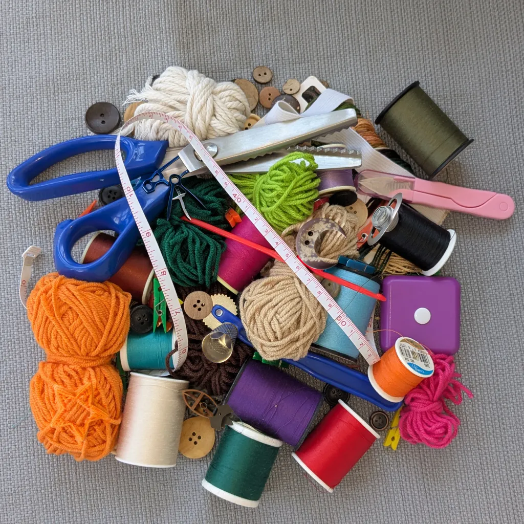 A The Daily Spy puzzle picture: a heap of yarn balls, thread spools, buttons, scissors and tape measures with small objects hidden among them