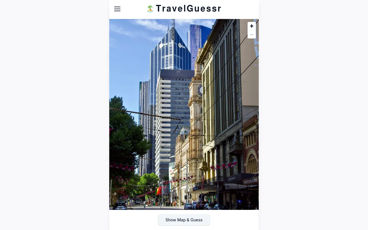 A TravelGuessr round: a city street photo of old stone shopfronts below glass towers, with zoom buttons and the Show Map & Guess button